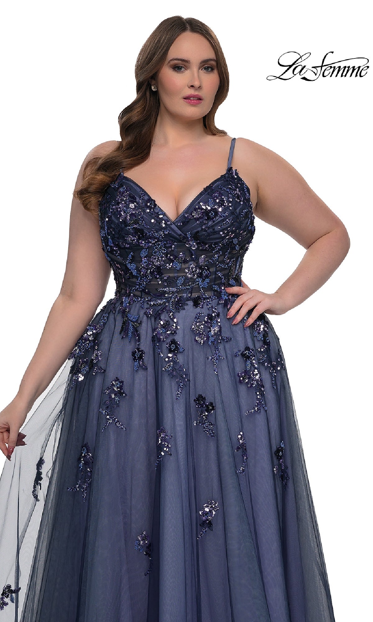 Woman models the Navy Plus-Size Prom Dress: La Femme 33061—an a-line gown with sequin floral appliqué and spaghetti straps—against a white background with the